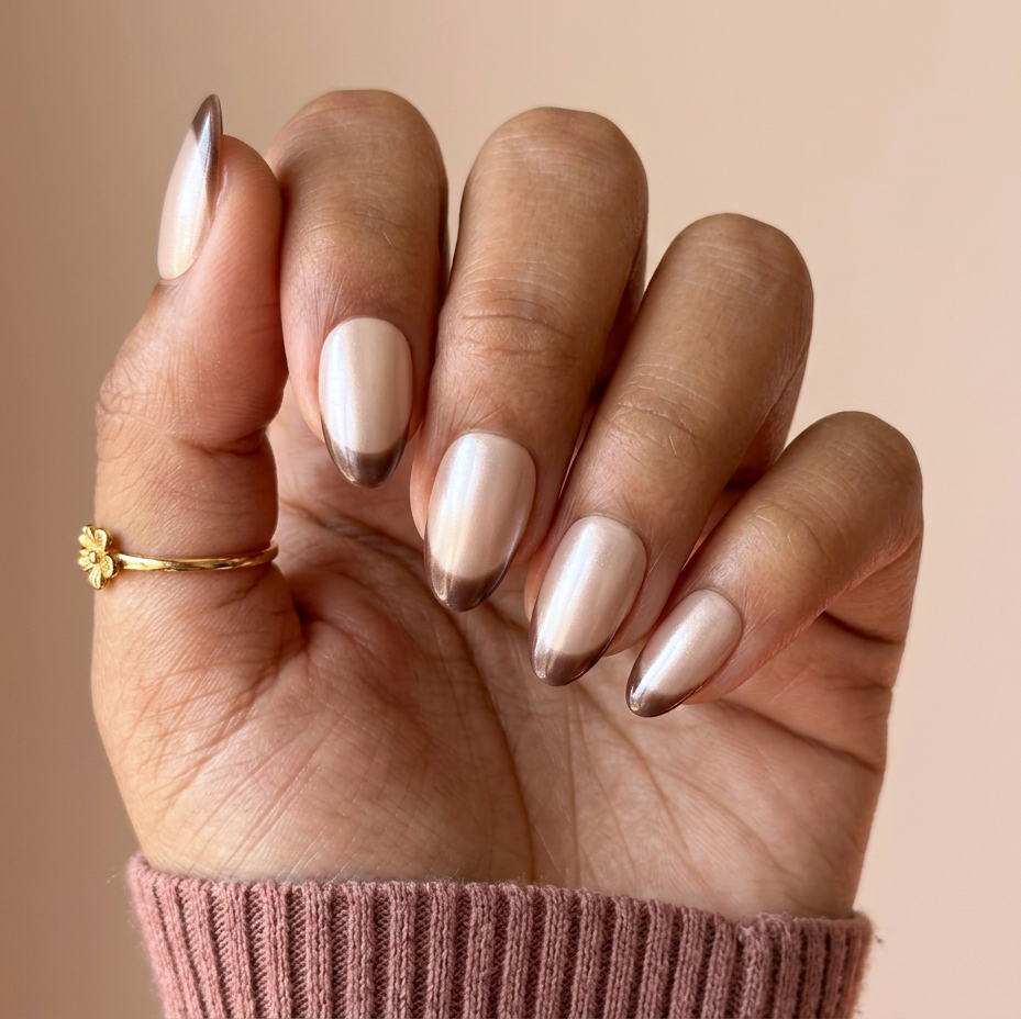 Hand with beige nail polish and a gold ring on a beige background