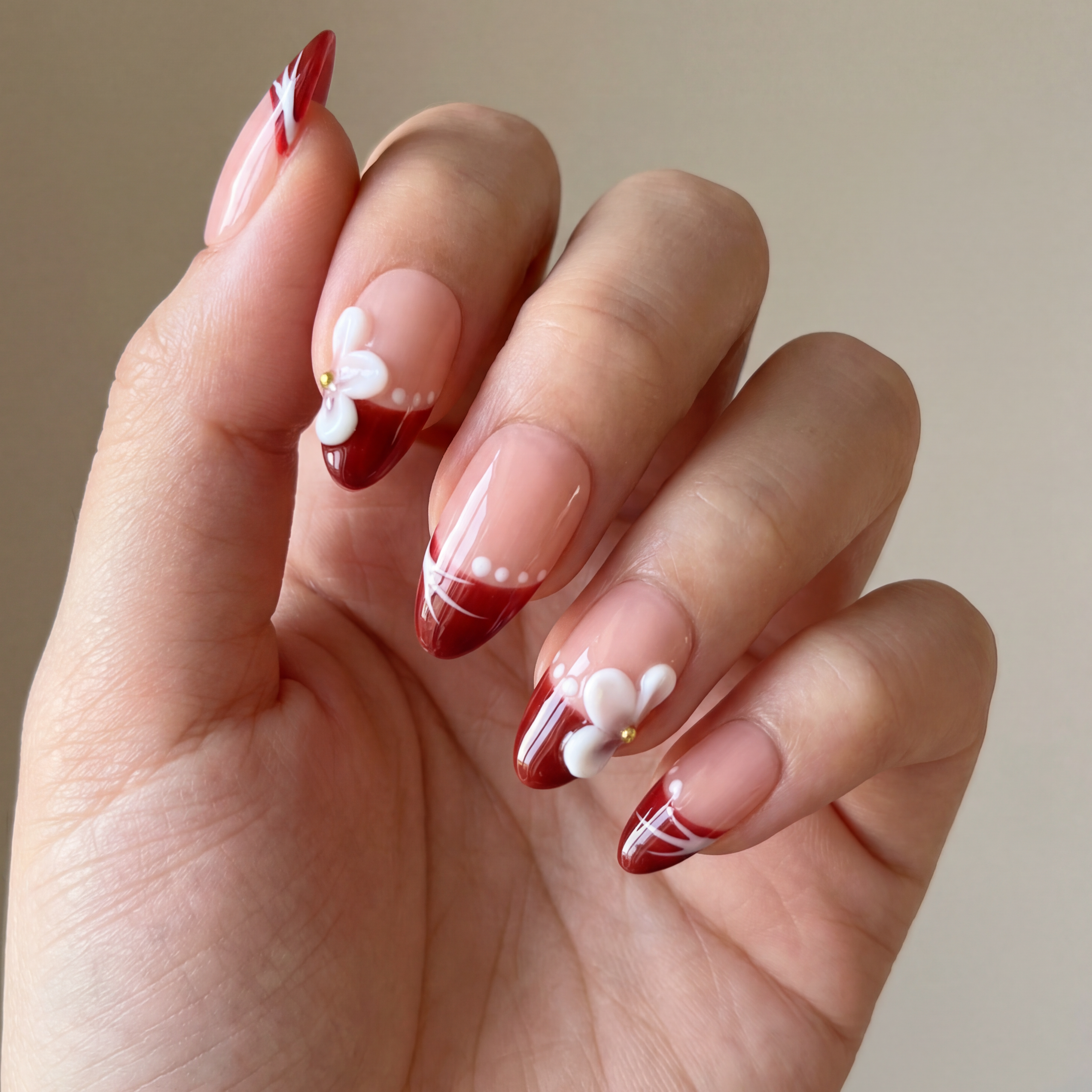 Hand with red and white nail design on a neutral background