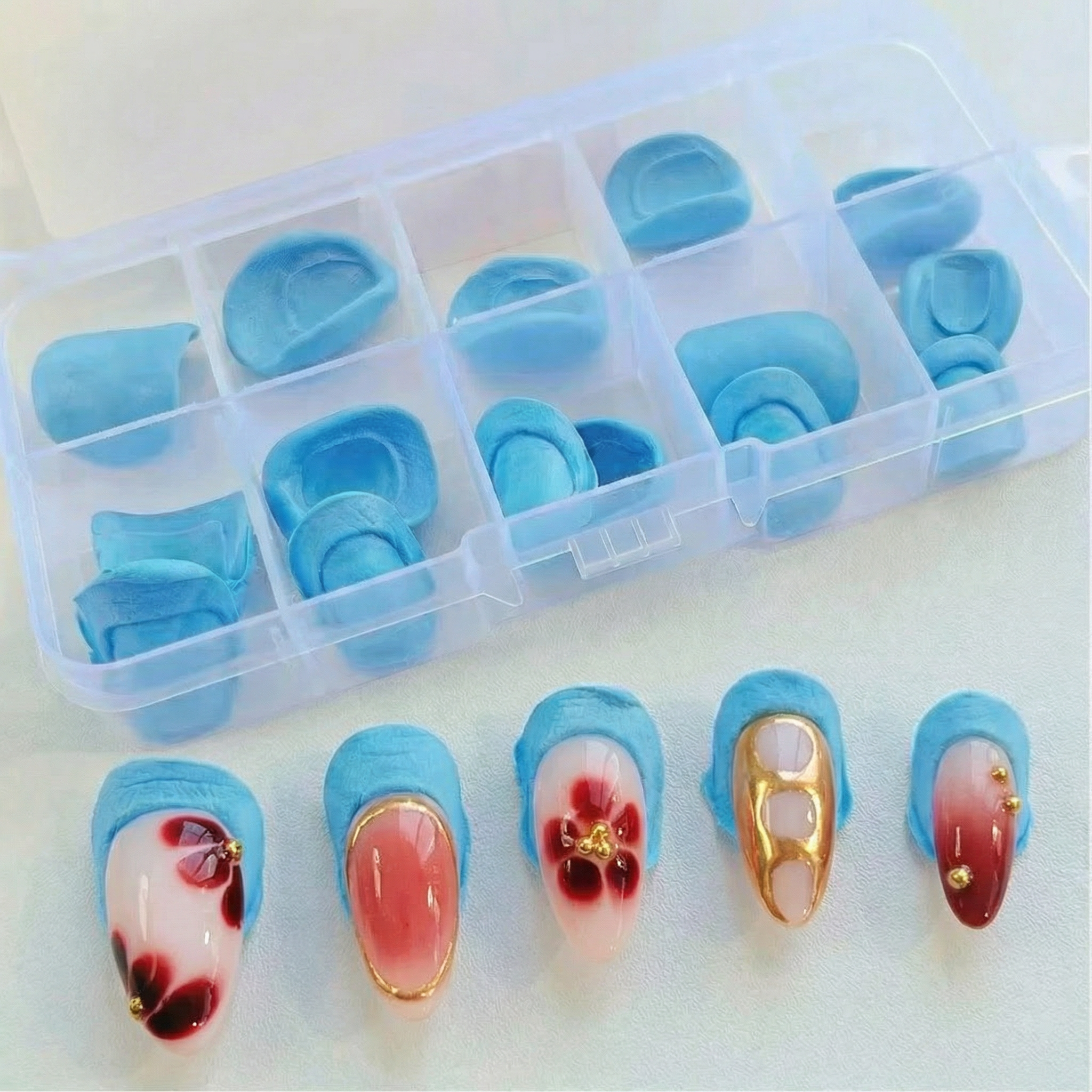 Set of blue nail art designs in a clear plastic case on a white background