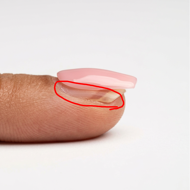 Close-up of a person's thumb with a pinky nail on a white background