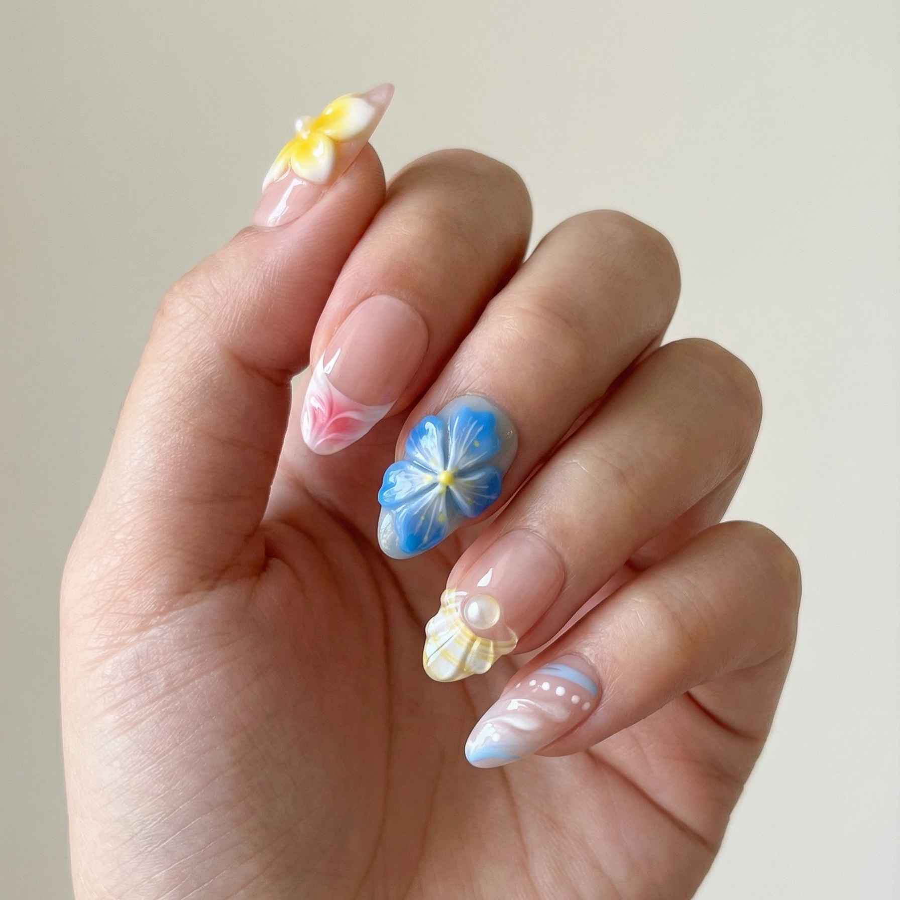 Hand with intricately designed nails featuring flowers on a plain background
